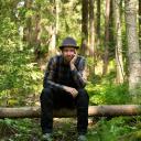 Juha Kauppinen istuu kaatuneen rungon päällä metsässä