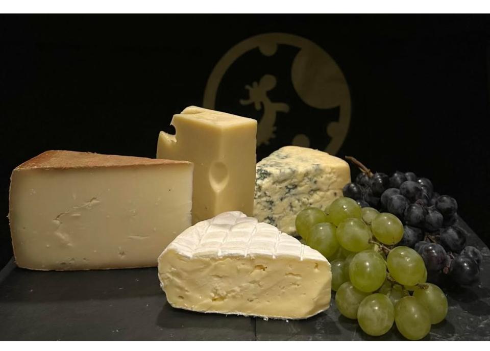 juustoja mustalla tarjottimella viiniryp&auml;leiden kera