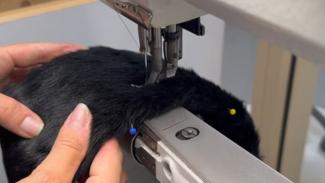 lähikuva mustasta karvapintaisesta hatusta, jota ommellaan koneella